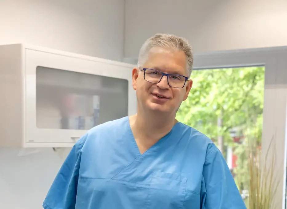 Dr. Dornbusch steht am Behandlungsstuhl und lächelt